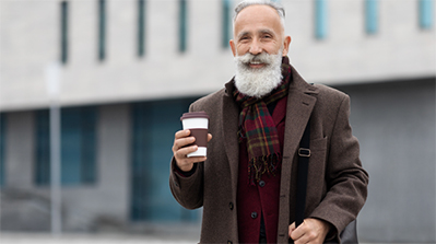 Man holding coffee on a cold day in front of a building